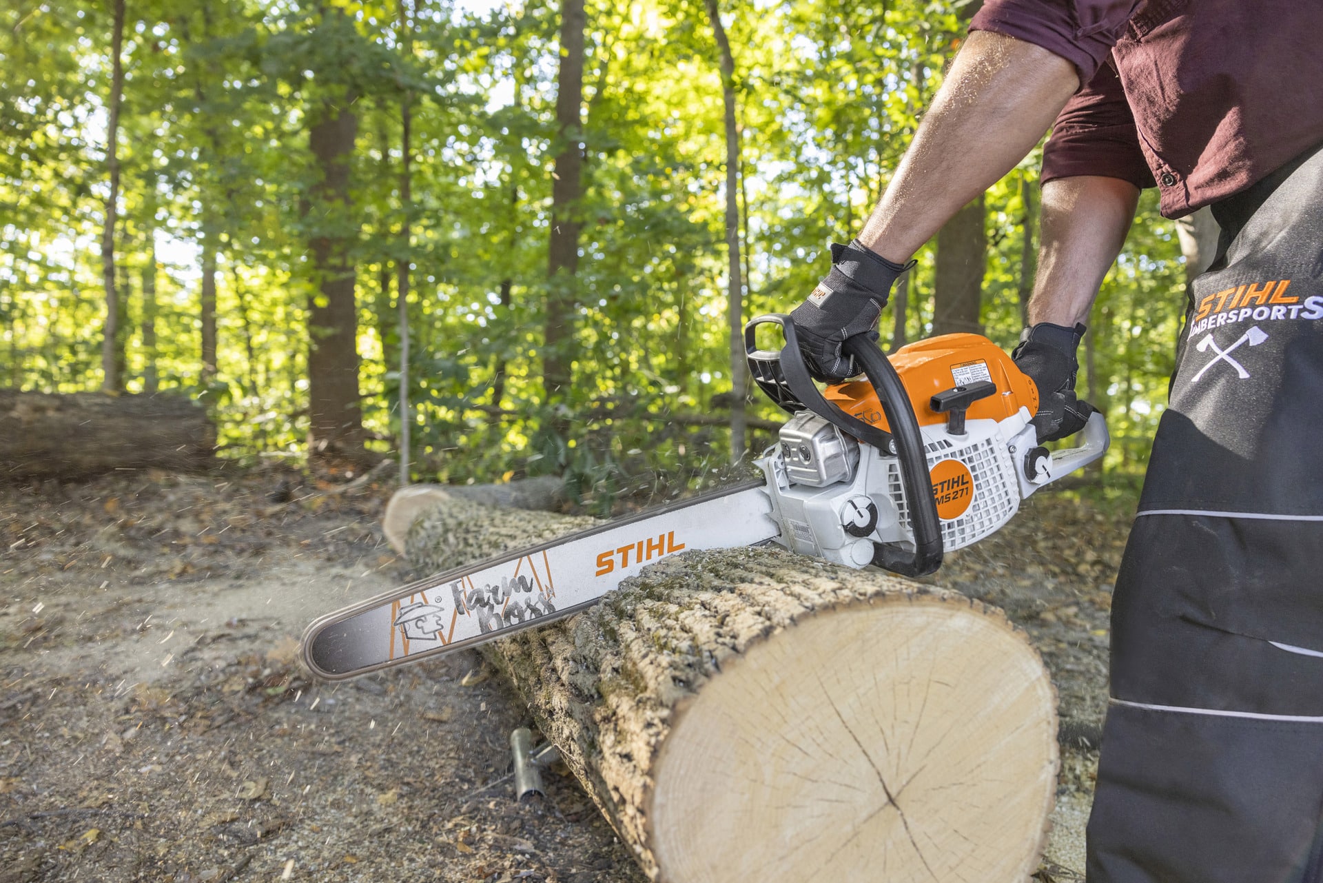 Person using a STIHL MS 271 chainsaw to cut a large log outdoors